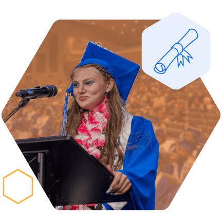 A student in a blue graduation cap and gown, standing at a podium and speaking into a microphone, giving a graduation speech