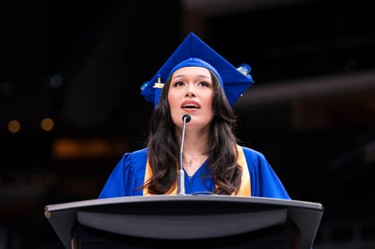Graduating student speaking on a podium at the graduation celebration