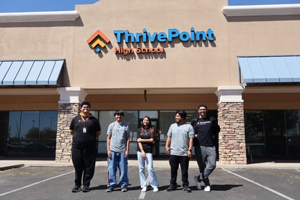 Students standing in front of the Avondale campus building with the ThrivePoint High School sign behind them