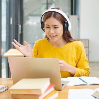 Estudiante mirando su portátil mientras lleva auriculares