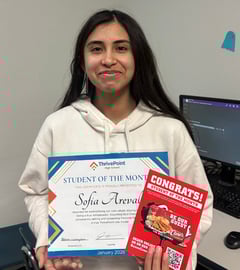 Student of the month student holding a certificate and raising canes gift card