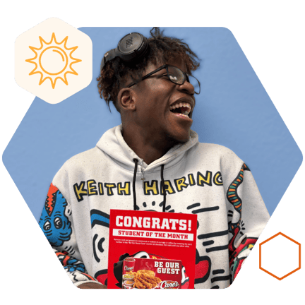 Student smiling looking to the side and holding a raising canes gift card for winning student of the month