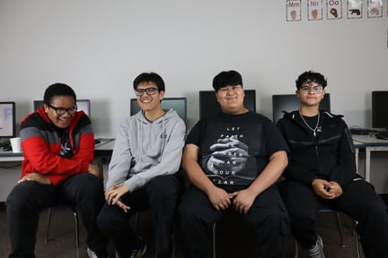 Students in the school computer lab sitting down smiling