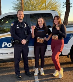 staff and police officer standing together holding medals from a 5k run