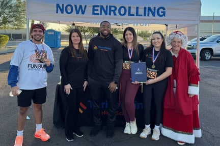 staff standing together at a tent with their 5k run medals