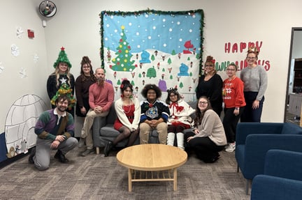 students and staff dressed up for the holidays sitting together in a campus common area (1)