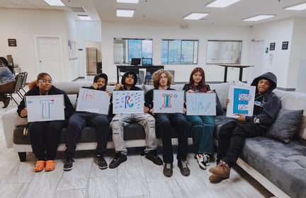students sitting down and holding a thrive sign