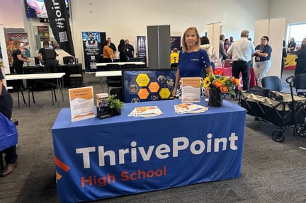 table with a thrivepoint high school blue cloth with swag items and buckeye learning center coordinator