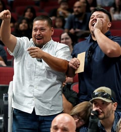 two adults in the arena stands cheering for their graduate