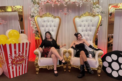 Students sitting down in big throne like white and gold chairs